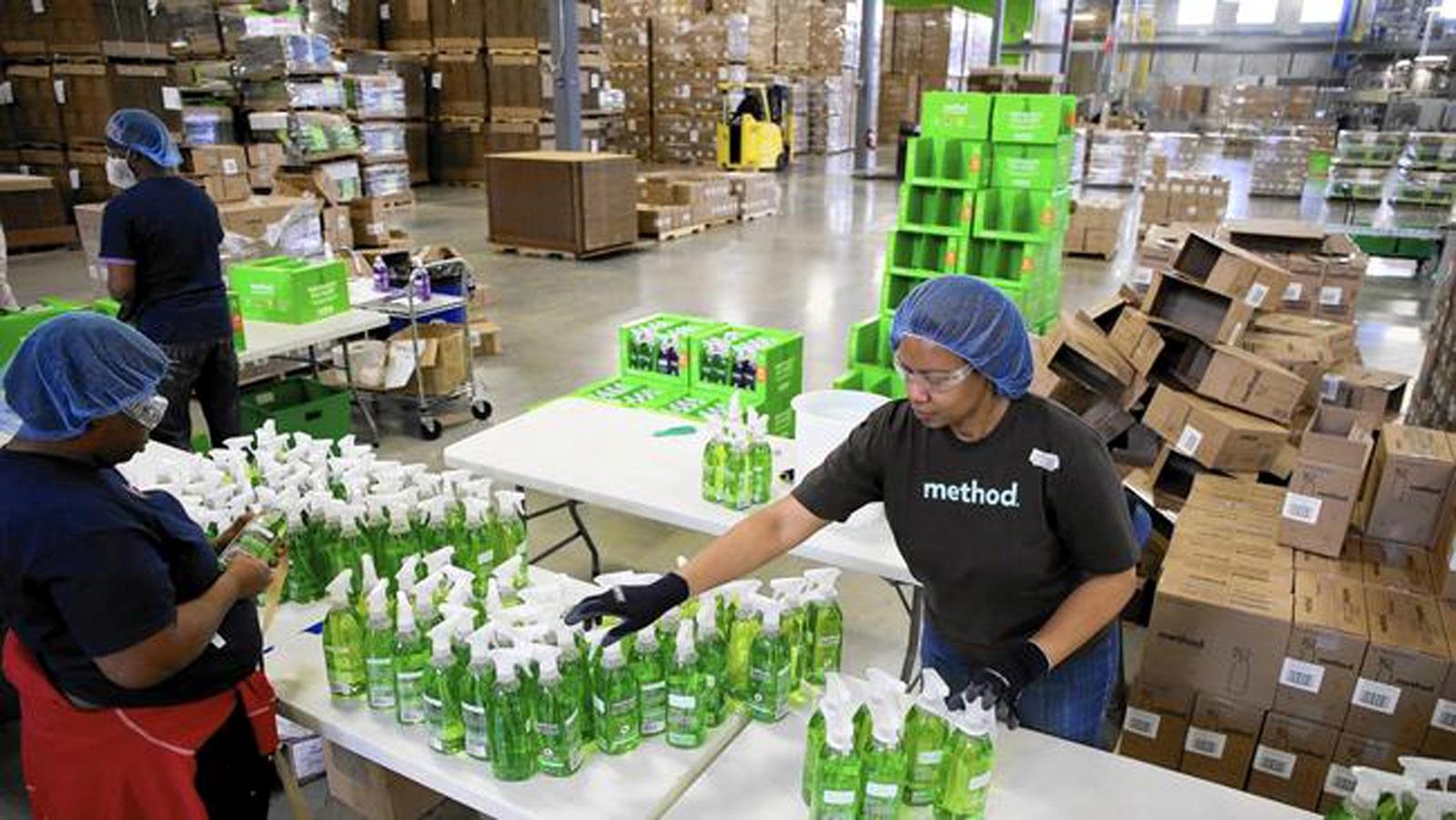 Emballages en carton et opératrice triant des bouteilles de savon vert