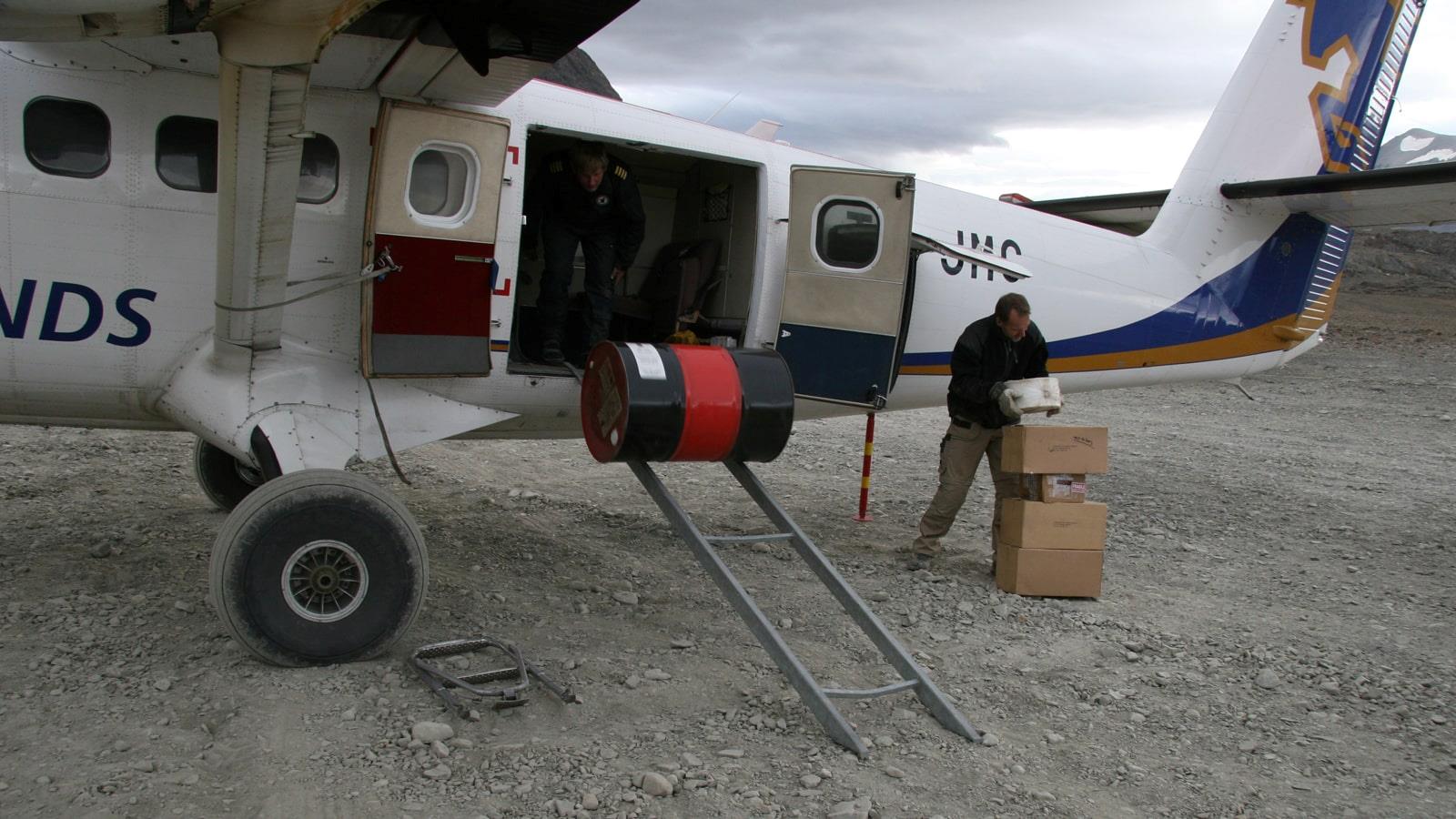 Des boîtes et un tambour déchargés d'un petit avion