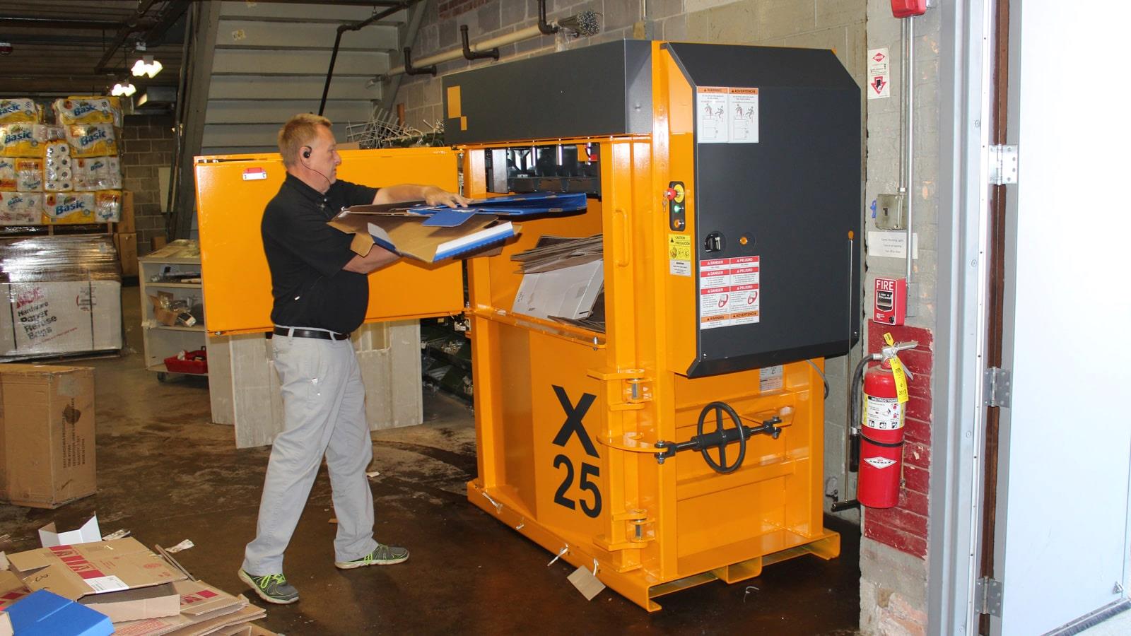 Opérateur chargeant de carton une presse à balles Bramidan installée dans un entrepôt 