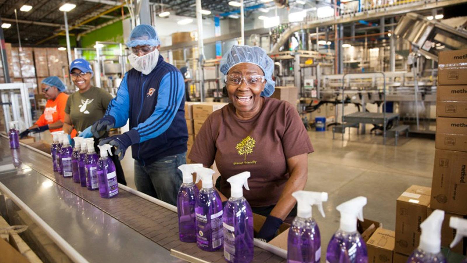 Employés portant des filets à cheveux sur une chaîne de production de bouteilles de savon