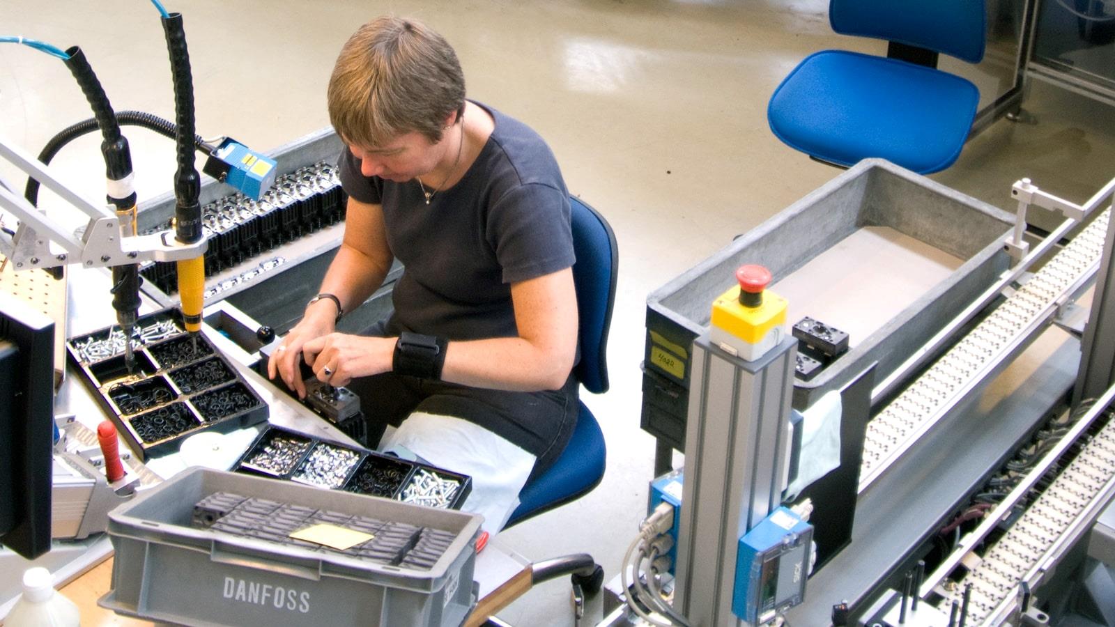 Une femme assemble des composants dans l’usine Sauer-Danfoss