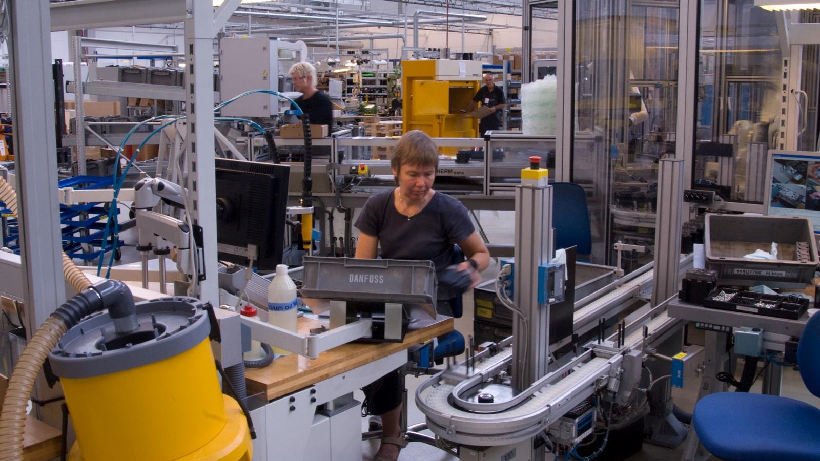 Employée dans l’usine Sauer-Danfoss avec au fond, une presse Bramidan