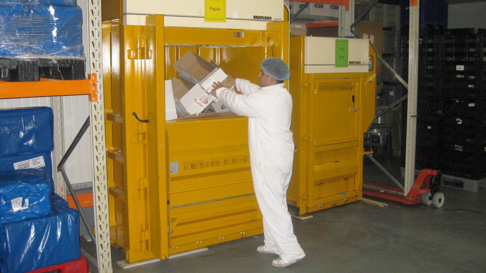 Un employé en combinaison hygiènique charge des résidus de carton