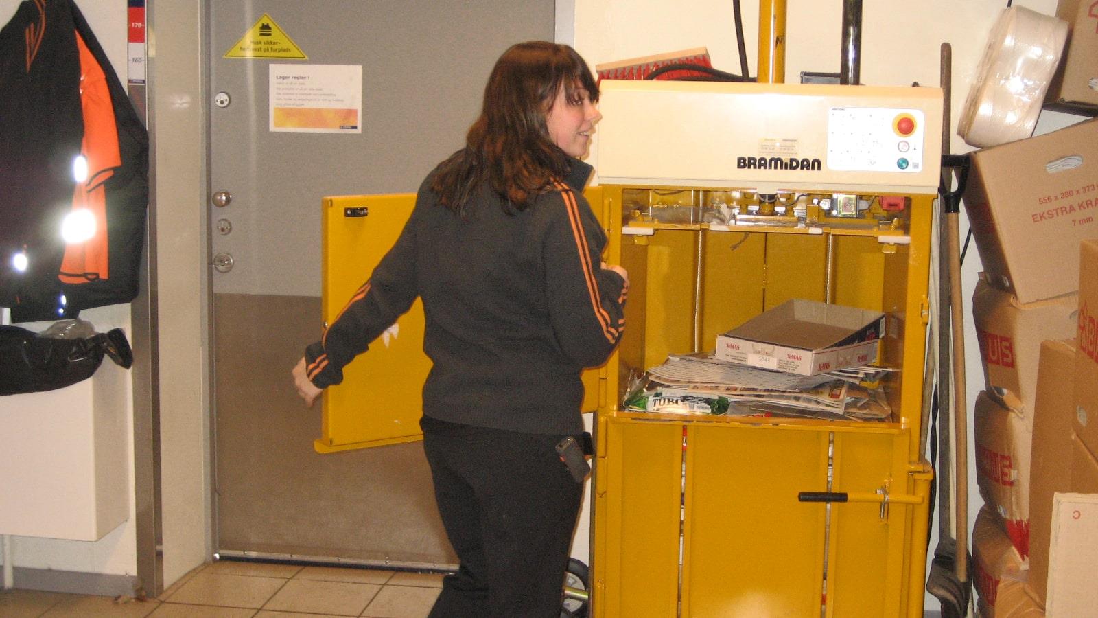 Une jeune employée ferme la porte d’une presse B3 après y avoir déposé du carton