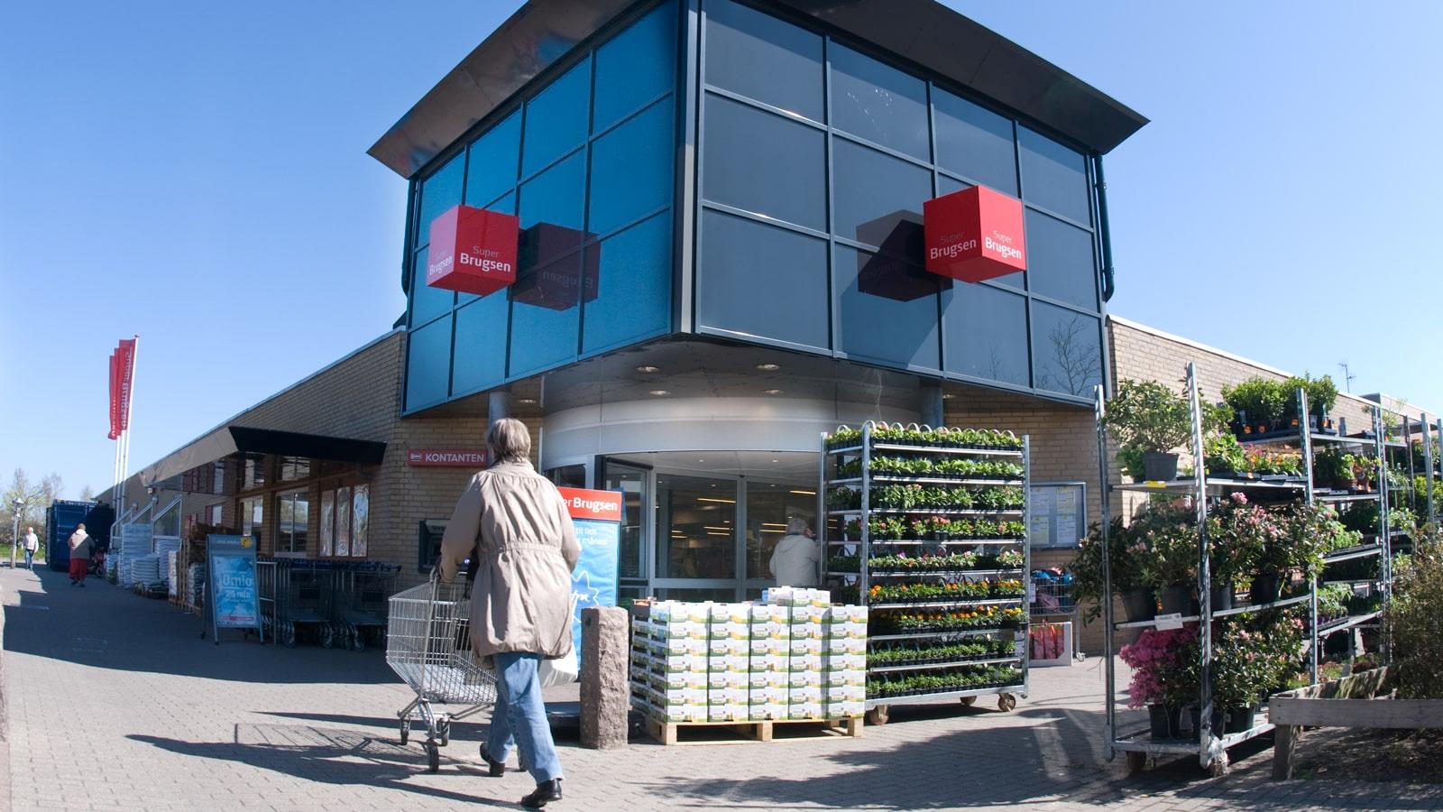 Une cliente pousse son caddie à l’entrée d’un supermarché SuperBrugsen à Graasten